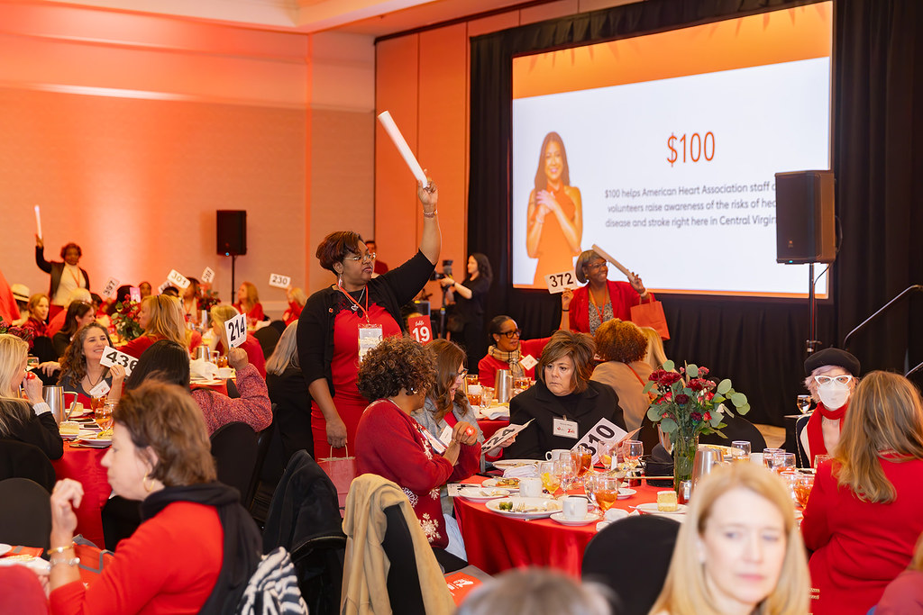 Attendees holding up bidder numbers to donate one hundred dollars.